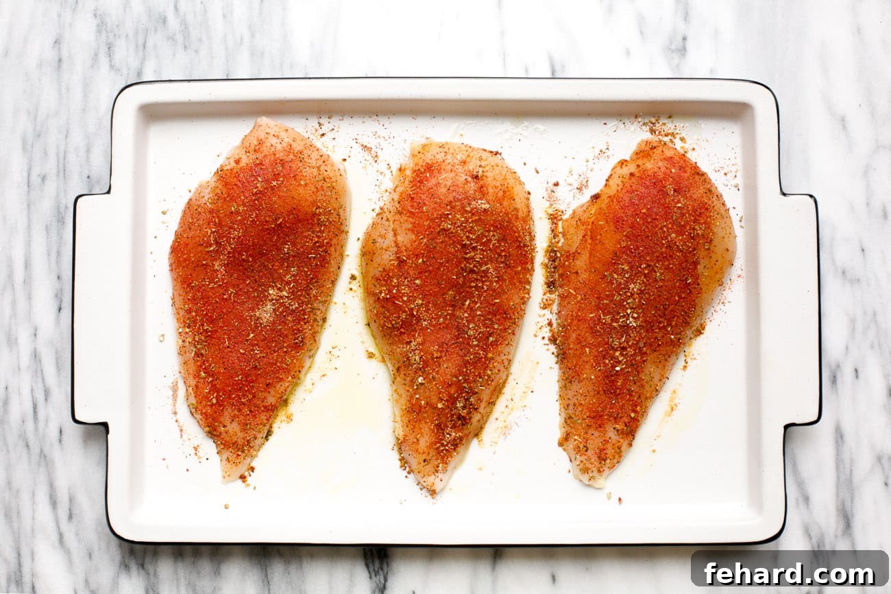 overhead view of seasoned raw chicken on a baking sheet