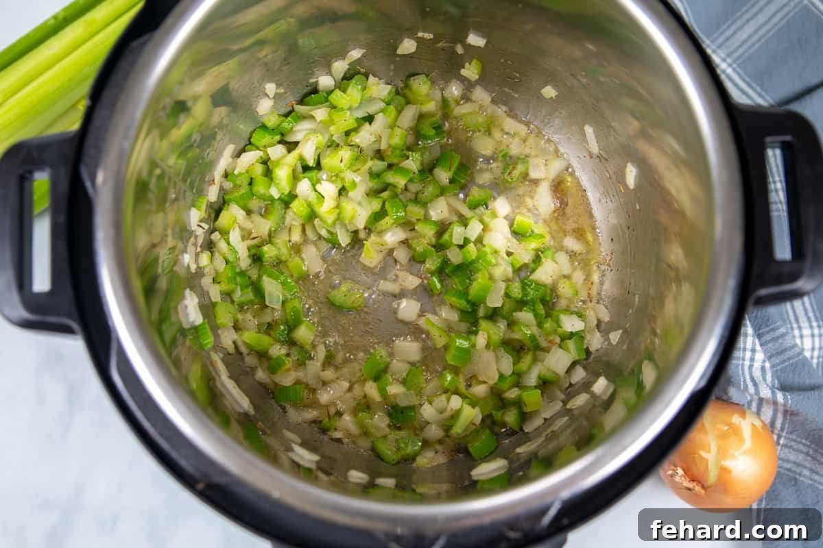 Minced onions and diced celery sautéing in melted butter in the Instant Pot inner pot, forming the aromatic base for the stuffing.