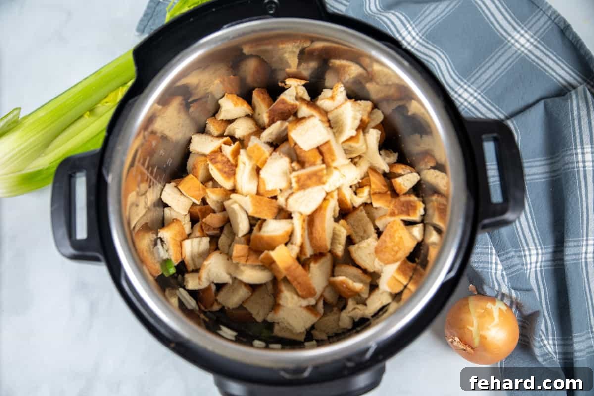 Dried bread cubes, sautéed aromatics, and broth mixed thoroughly in the Instant Pot inner pot, ready for pressure cooking.