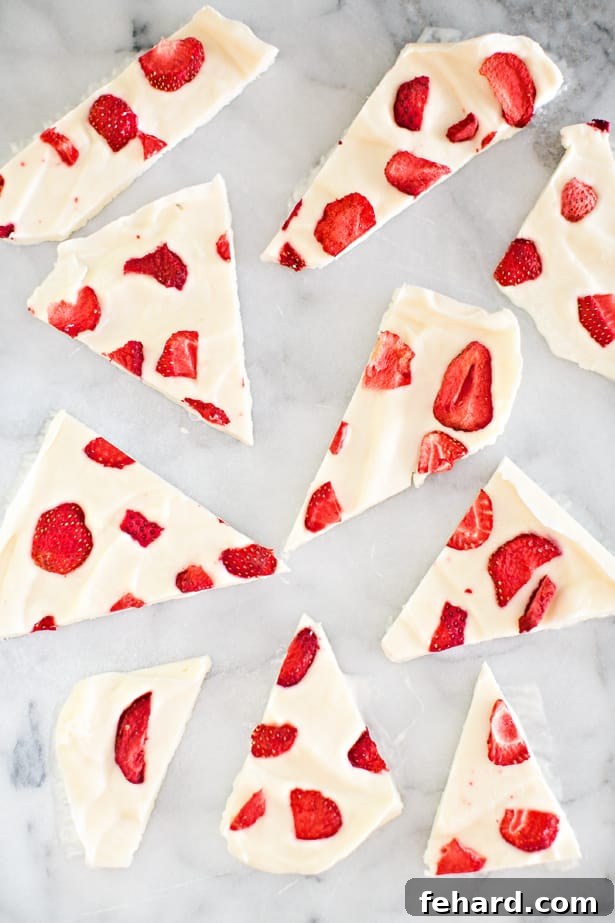 Irregular pieces of white frozen yogurt bark speckled with bright red strawberry fragments, creating an appealing visual.