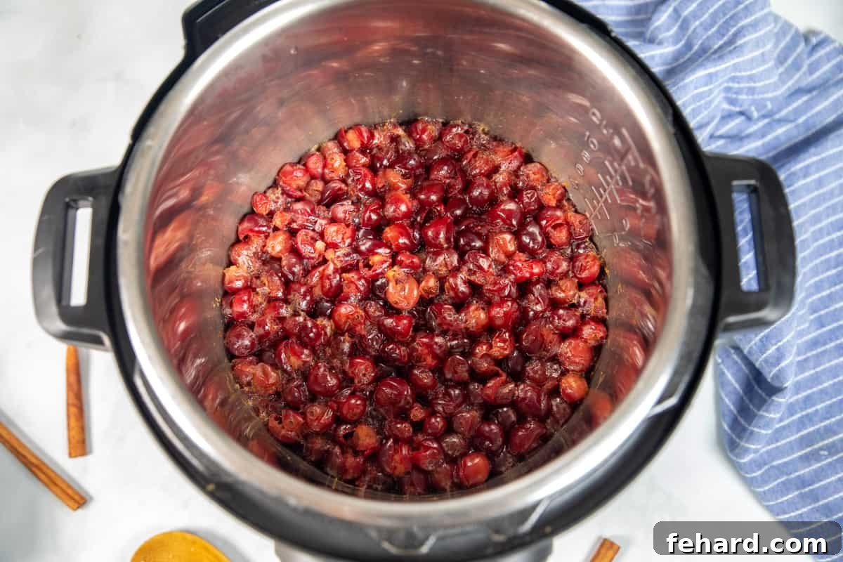 Instant Pot Cranberry Orange Sauce Perfectly cooked cranberry sauce simmering inside the Instant Pot, its vibrant color and softened cranberries indicating readiness.
