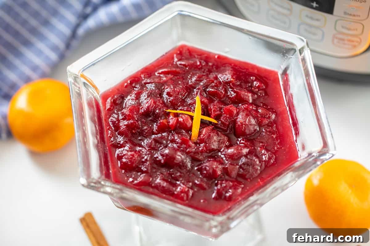 Pressure Cooker Cranberry Sauce Smooth, chilled cranberry sauce, beautifully garnished with fresh orange zest, presented next to the clean Instant Pot inner pot.