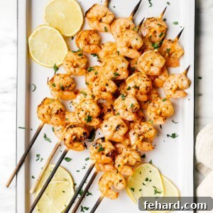 Overhead view of perfectly grilled shrimp on a white platter, garnished with fresh lemon and parsley, ready to be enjoyed.