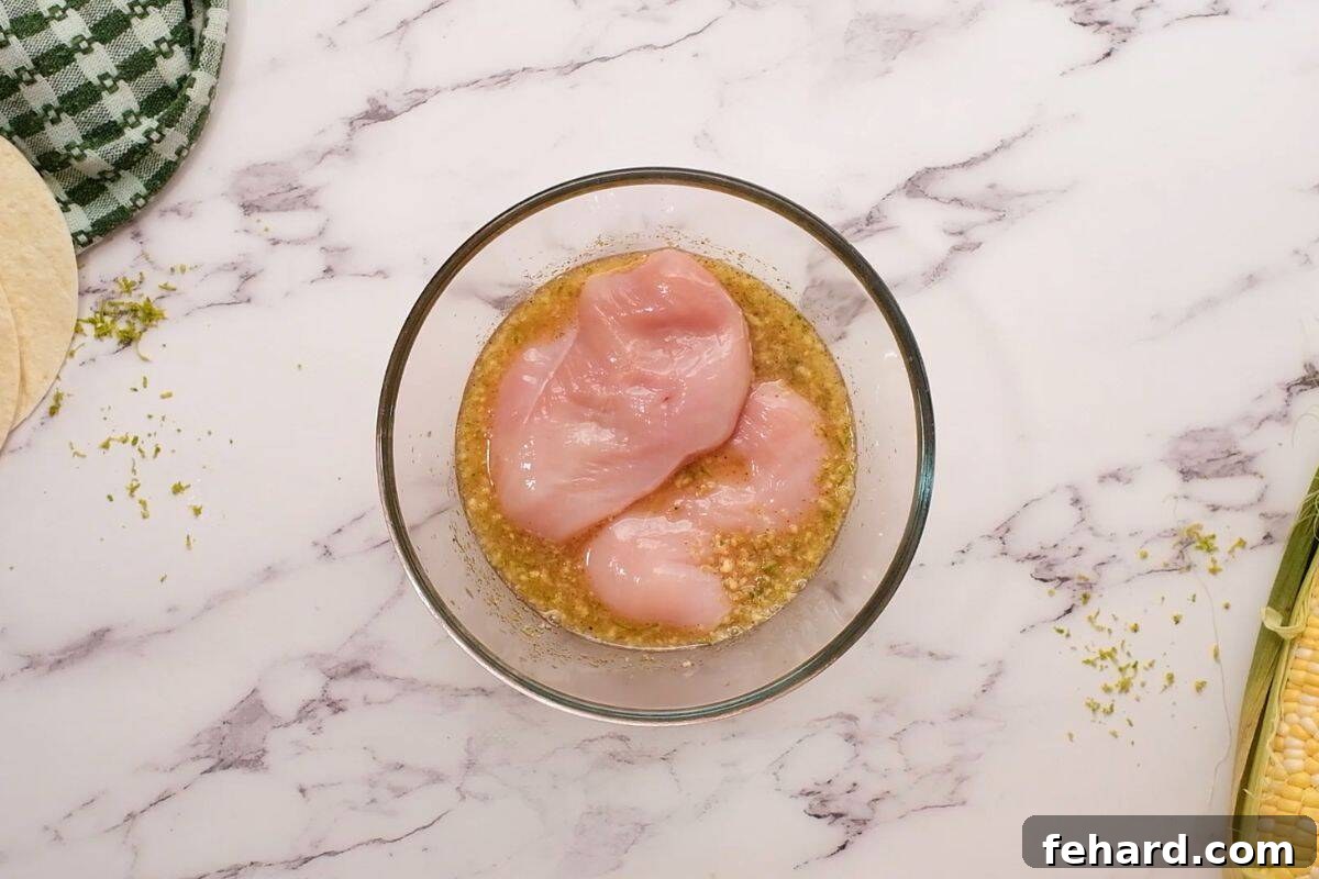 Chicken breasts soaking in a vibrant honey lime marinade in a glass dish, ready for grilling.