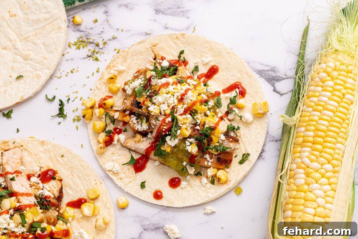 A beautifully assembled Grilled Honey Lime Chicken Fajita on a flour tortilla, garnished with grilled corn, salsa verde, and fresh cilantro.