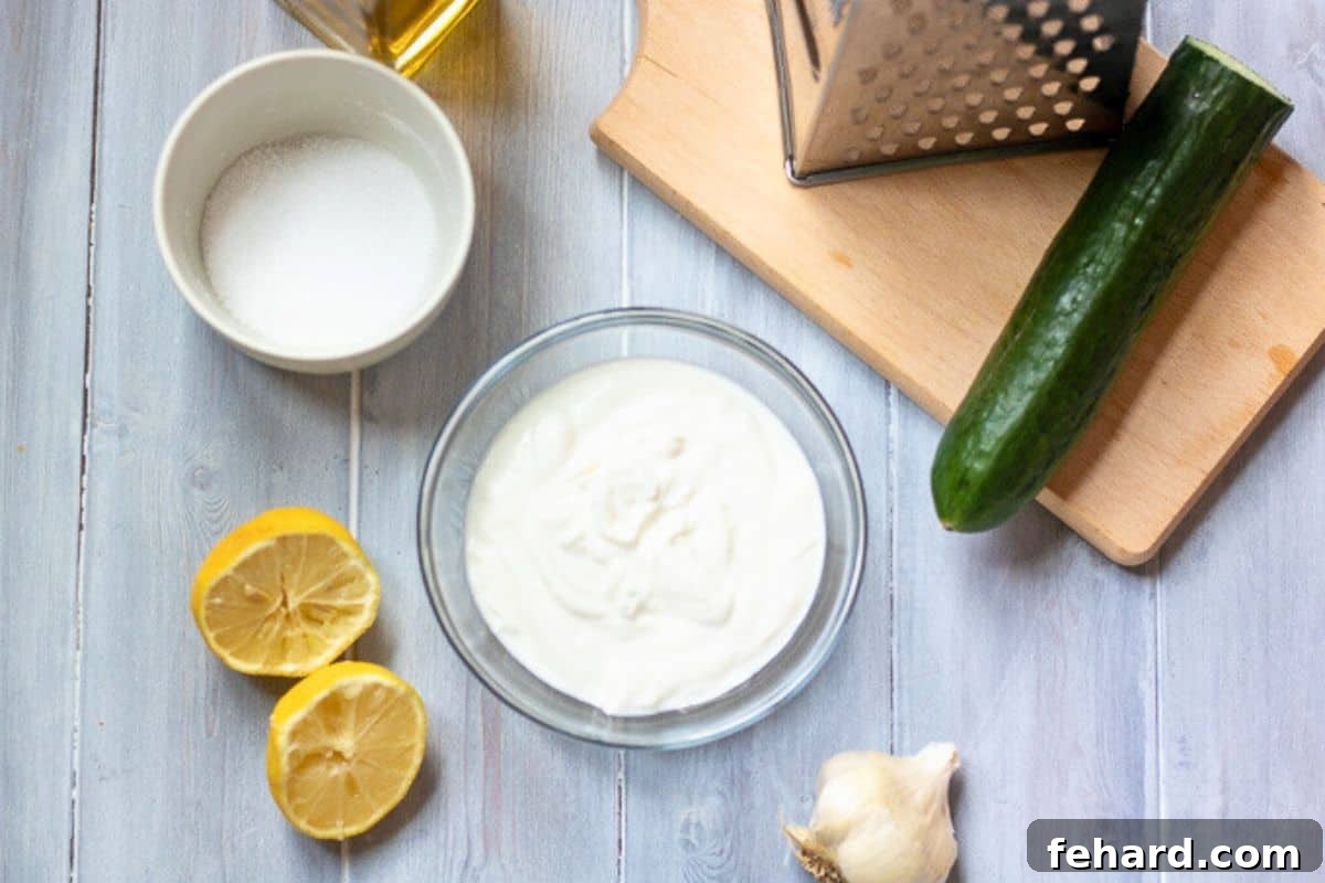 Tzatziki Recipe A selection of fresh ingredients laid out on a kitchen counter for making Tzatziki sauce, including creamy Greek yogurt, vibrant lemons, fresh garlic cloves, crisp cucumbers, and fragrant dill.