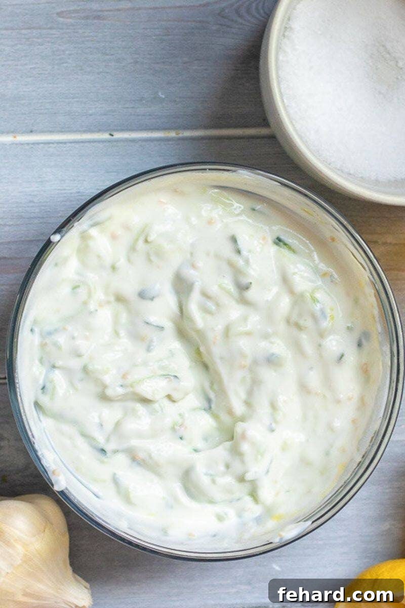 Authentic Homemade Tzatziki 3 A mixing bowl with all the Tzatziki sauce components already combined and stirred together, showing a creamy texture.
