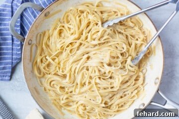 Alfredo noodles in skillet after being cooked in light sauce until pasta is tender.
