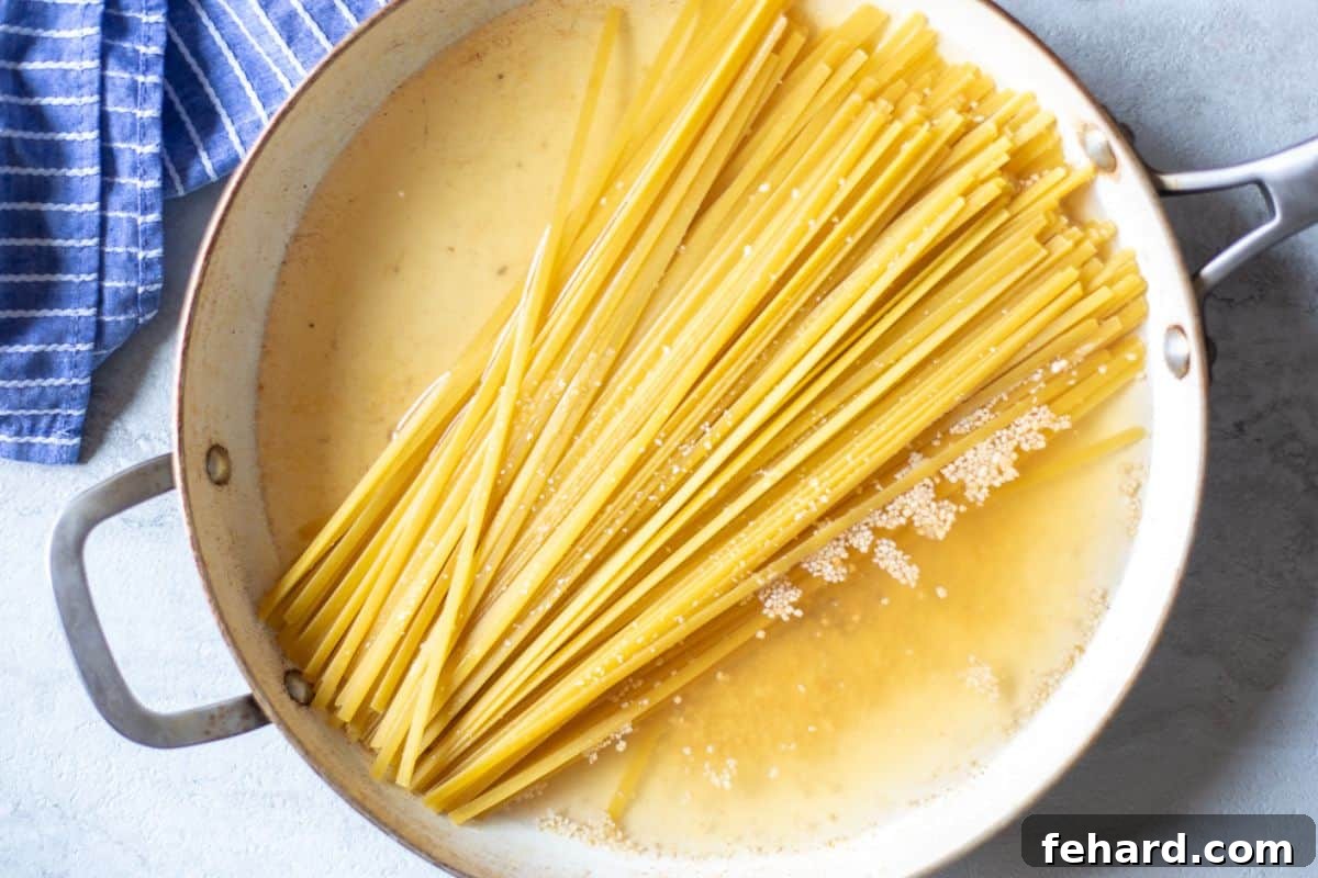 Broth, fettuccine noodles, and garlic in 12-inch skillet, ready to cook for 15-minute alfredo.