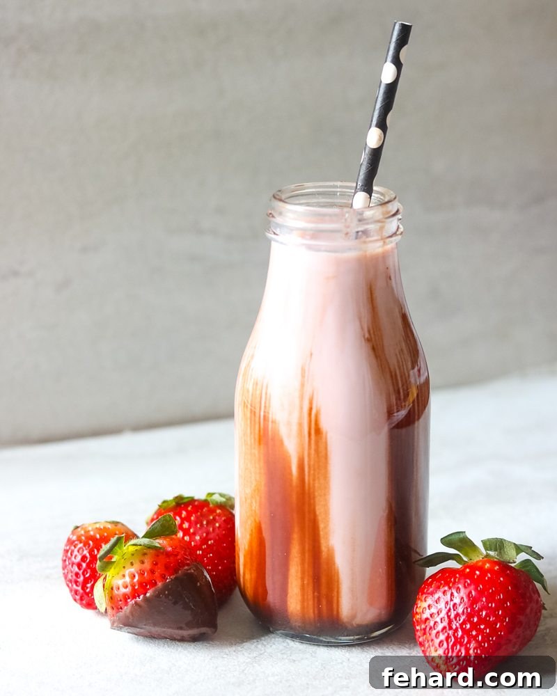 A clear glass bottle filled with a vibrant pink strawberry smoothie, with rich melted chocolate artfully drizzled down its sides. The perfect blend of fruit and chocolate.