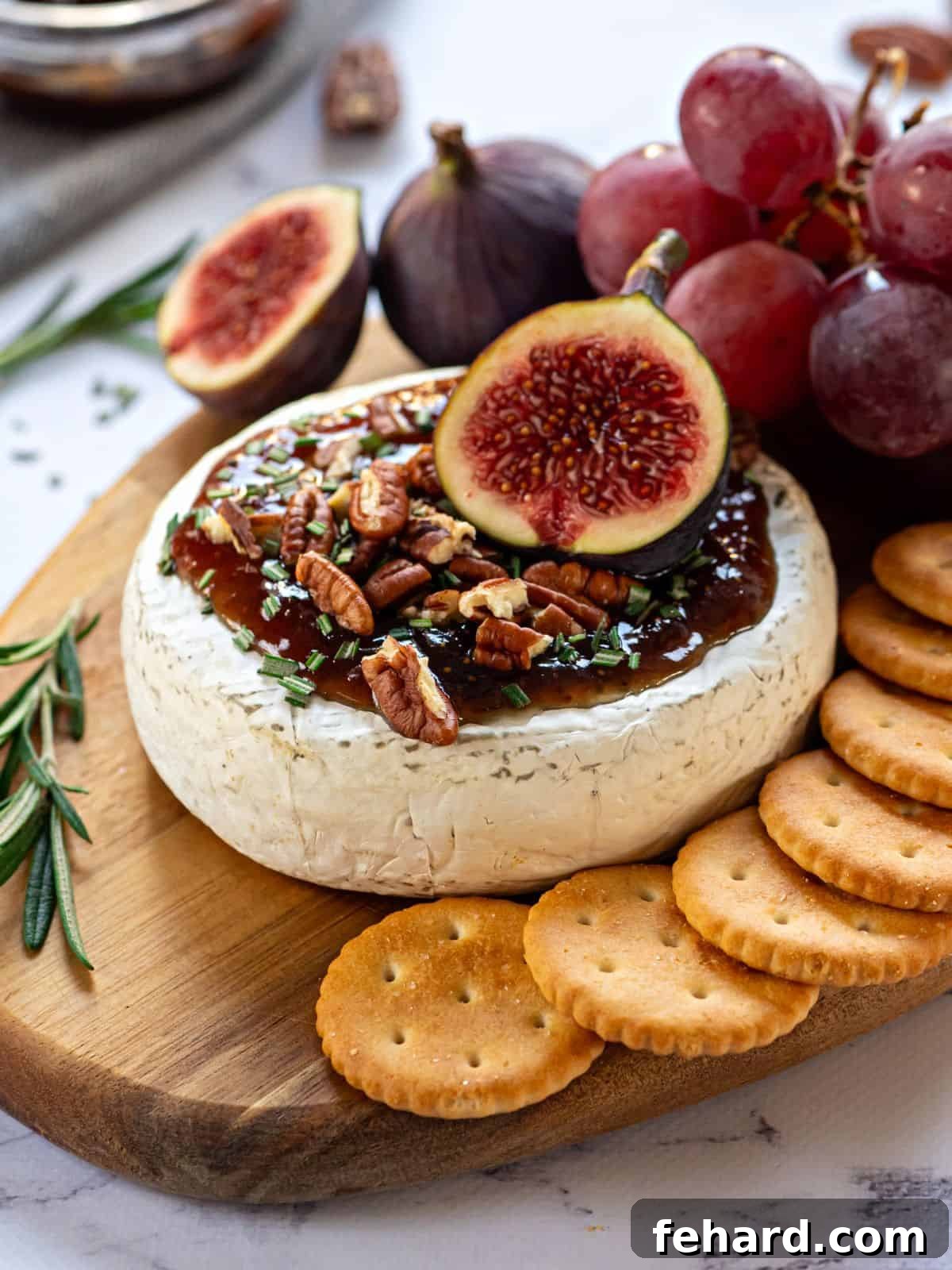 A perfectly baked brie on a rustic cutting board, adorned with glistening fig jam, crunchy walnuts, and fresh figs, ready to be served as an irresistible appetizer.