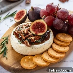 Baked Brie on cutting board topped with fig jam, walnuts, and fresh figs.