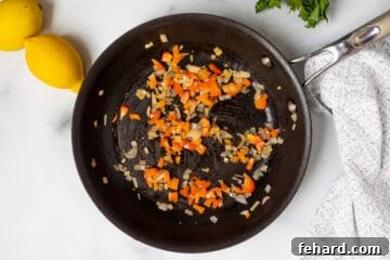 Sauteed pepper and shallots in frying pan.