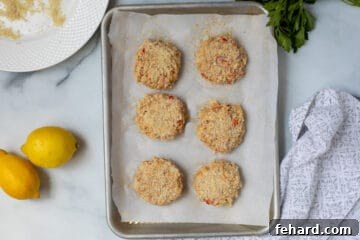 Shaped and breaded Crab Cakes on baking sheet.