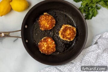 3 crab cakes in frying pan.