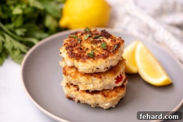 Crab Cakes stacked on top of each other on gray plate with lemon in the background.