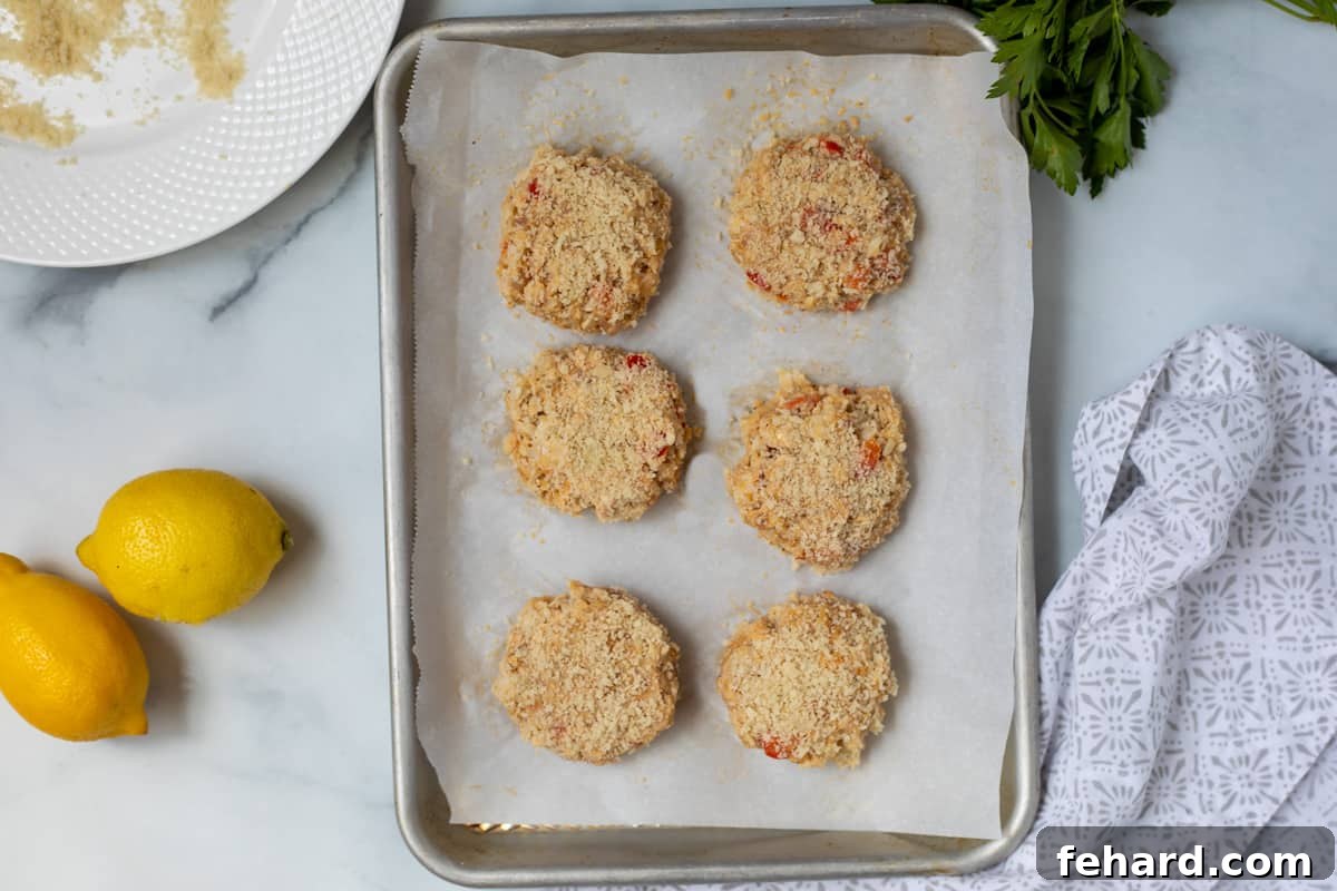 A baking sheet filled with neatly shaped and Panko-breaded crab cakes, ready for cooking, showcasing their uniform size and crispy coating.