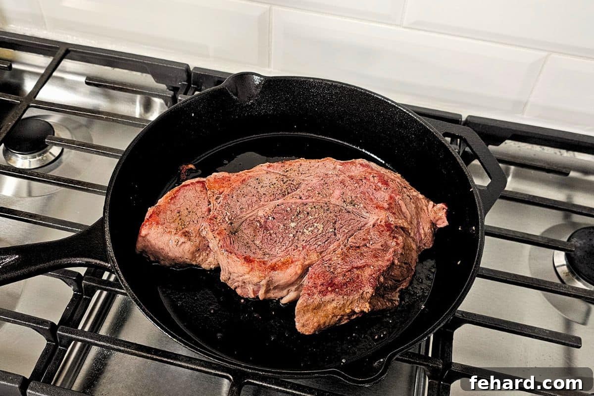 A perfectly seared chuck roast resting in a Dutch oven skillet, showing its rich, browned exterior.