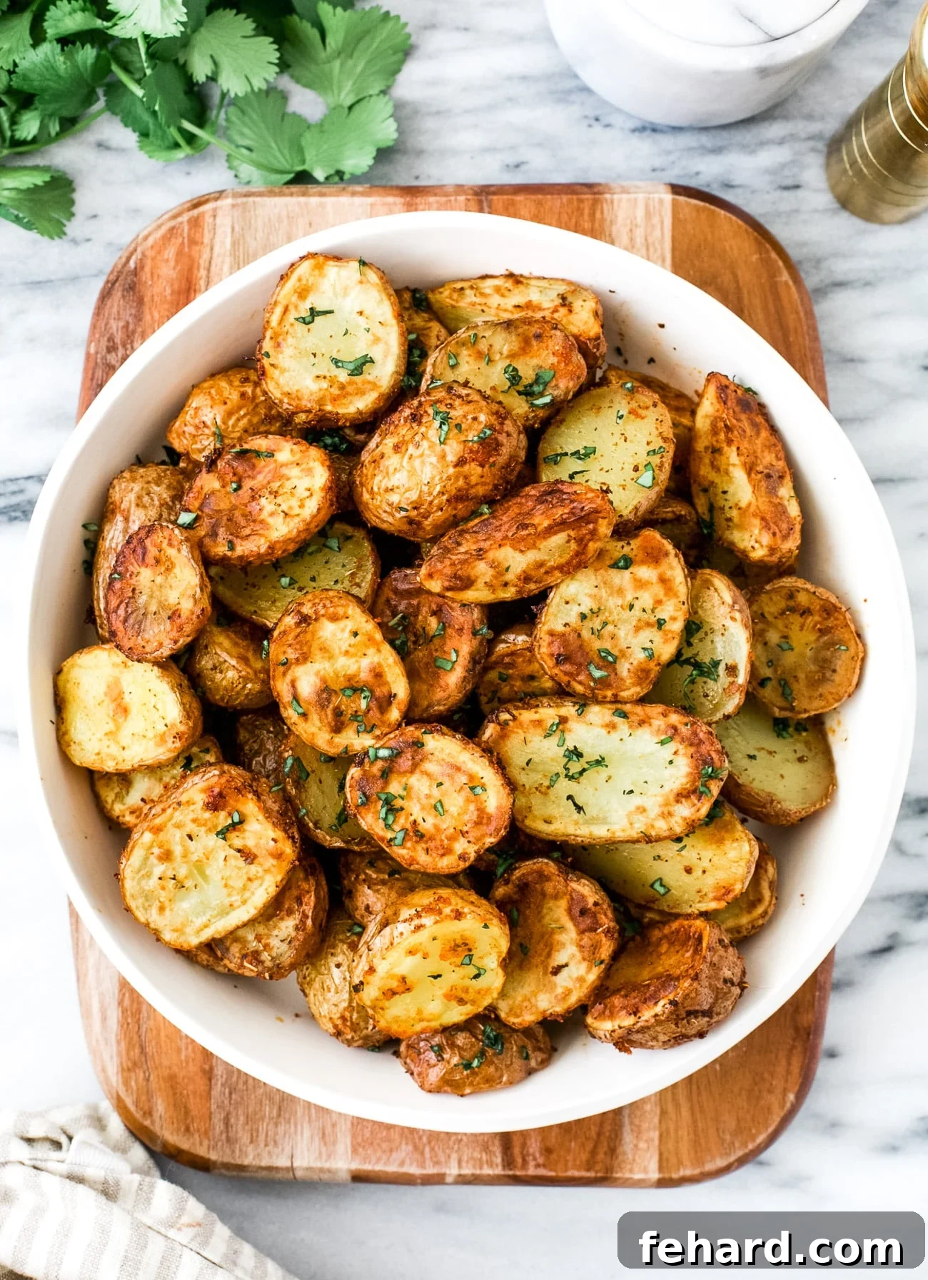 A top-down view of perfectly golden and crispy air fryer baby potatoes arranged artfully in a white serving plate, ready to be enjoyed.