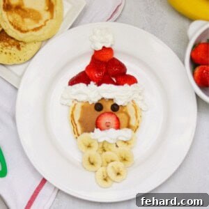 A close-up view of a cheerful Santa pancake, complete with a strawberry hat, banana beard, and whipped cream accents. This festive breakfast is ready to bring smiles to any holiday morning.