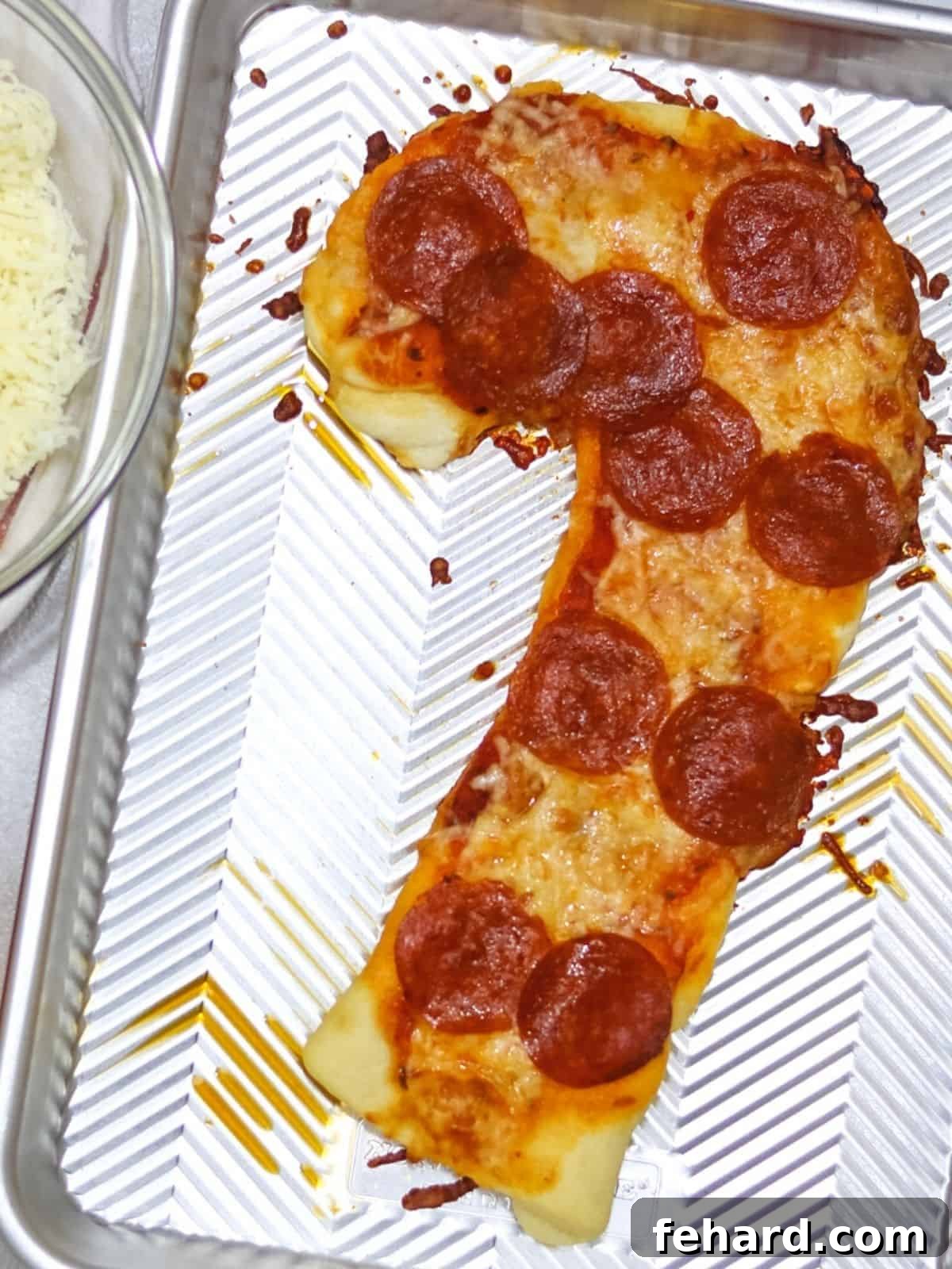 Candy Cane Shaped Pepperoni Pizza on a baking sheet, beautifully baked and ready to serve.