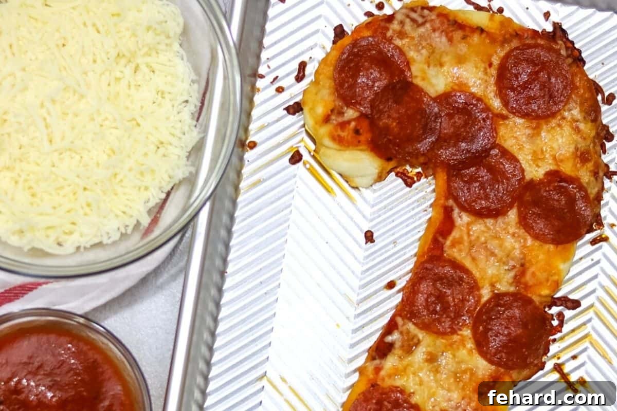 Baked Pepperoni pizza on a sheet pan shaped like a candy cane, golden and ready to slice.