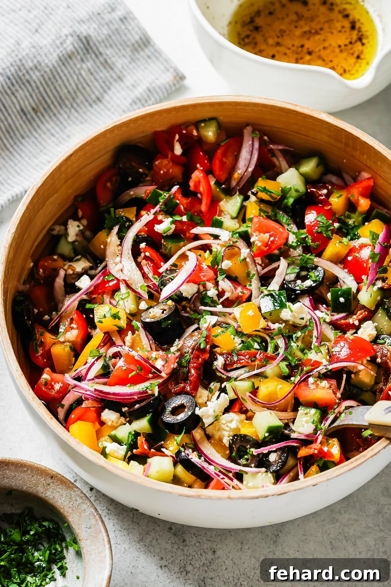 overhead view of a vibrant Mediterranean Salad in a white bowl, featuring cherry tomatoes, cucumbers, bell peppers, feta, and olives