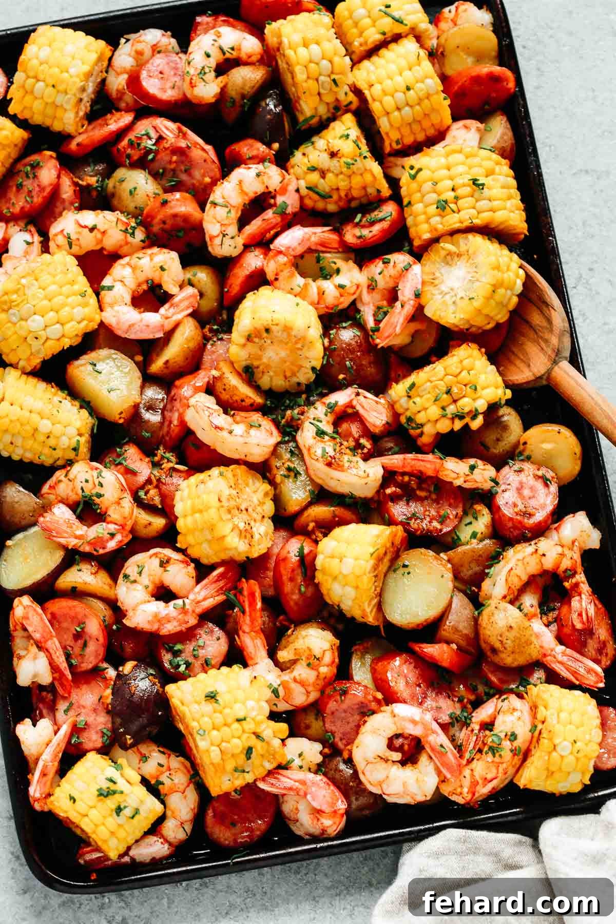 Easy One Pan Shrimp Boil 5 close up of shrimp boil sheet pan dinner, showing the crispy edges of sausage and potatoes, and perfectly pink shrimp