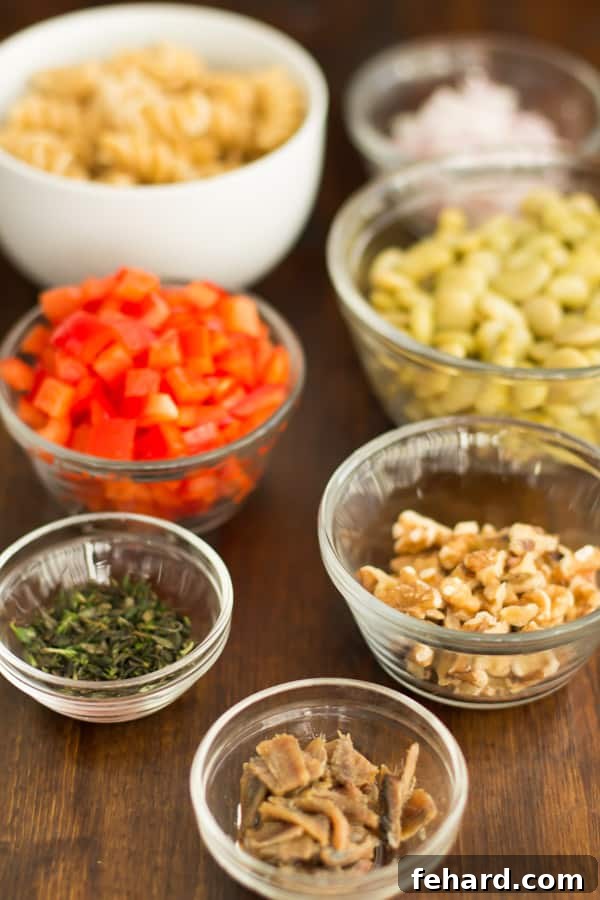 cut pasta salad ingredients in prep bowls: whole wheat fusilli, baby lima beans, bean sprouts, red onion, red peppers, fillets of anchovies, chopped fresh thyme