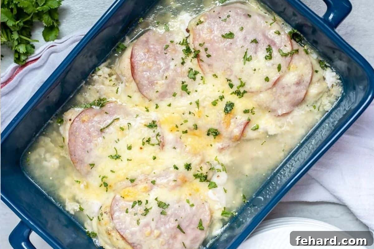Chicken topped with ham and swiss cheese baked in blue baking dish for easy version of Chicken Cordon Bleu.