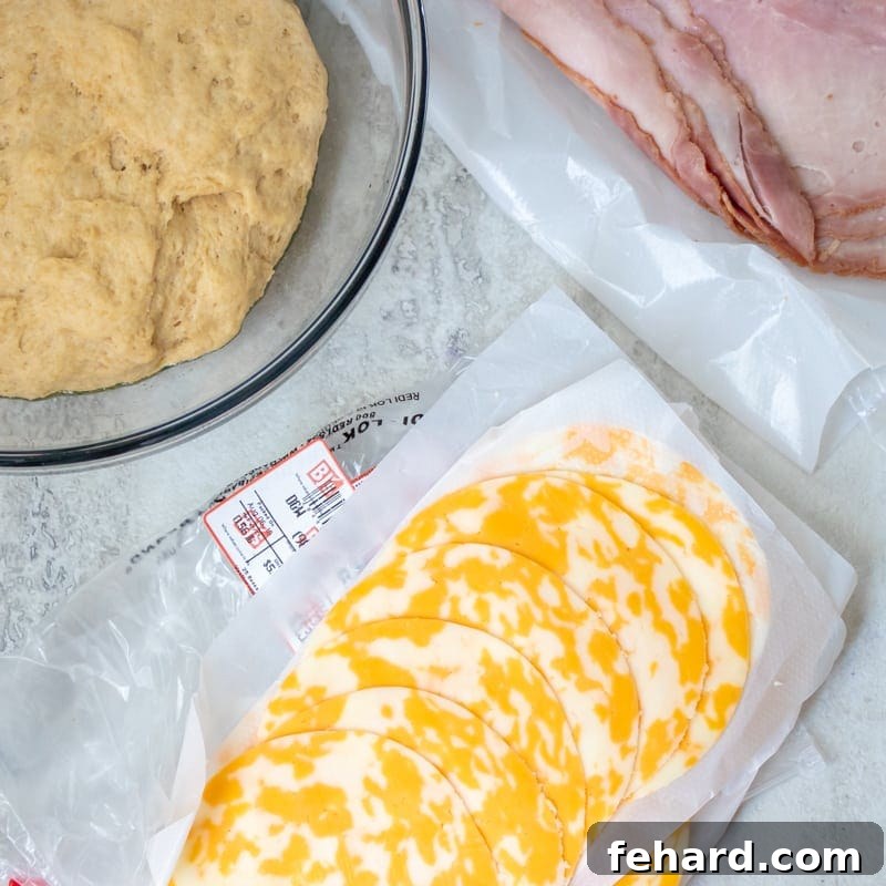 Deli Ham and Cheese slices arranged next to freshly rolled pizza dough, ready for hot pocket assembly.