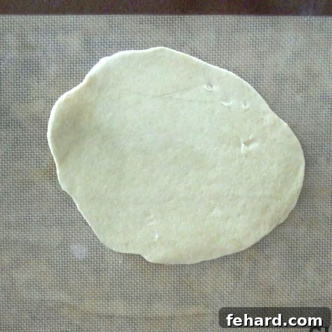Eight uniformly rolled hot pocket dough ovals arranged on a silicone baking mat.