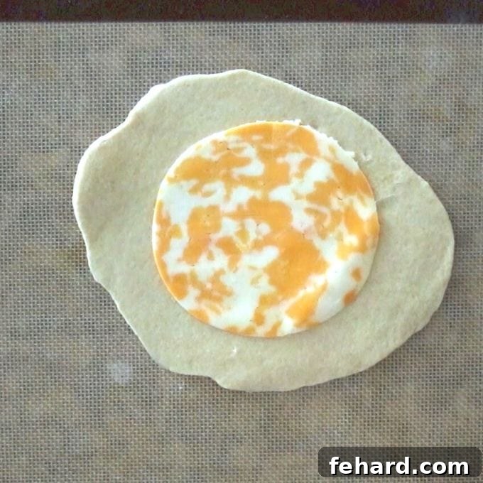Close-up of shredded cheese topping the middle of a rolled-out hot pocket dough oval.
