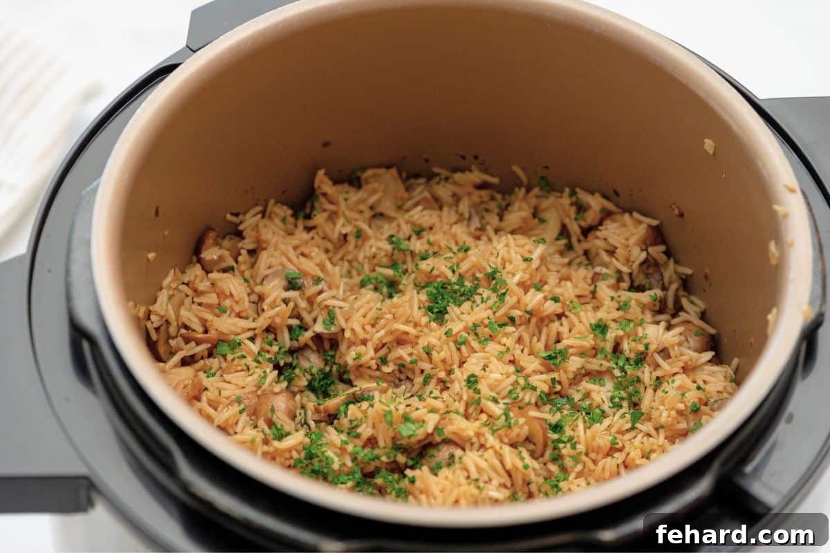 Cooked rice pilaf inside the Instant Pot, topped with fresh parsley, ready to be fluffed.