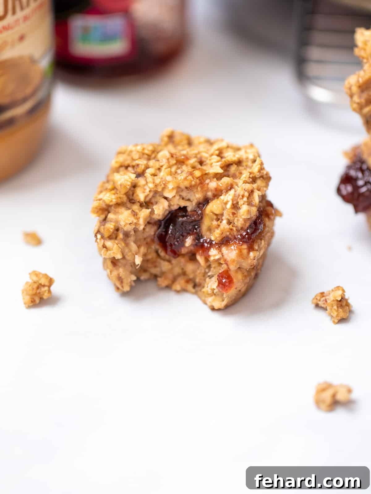 A baked oatmeal cup with a visible jelly filling oozing from the center, showcasing its delicious texture and filling, perfect for a healthy breakfast.