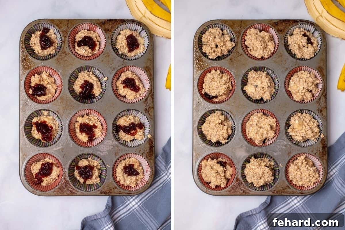 A muffin tin with some cups filled halfway with oatmeal batter and others with a dollop of jelly on top, ready for the final batter layer, for healthy oatmeal cups.
