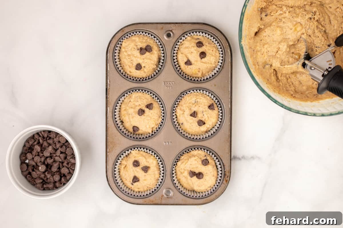 Banana Peanut Butter Muffins in muffin tin topped with additional chocolate chips before baking.