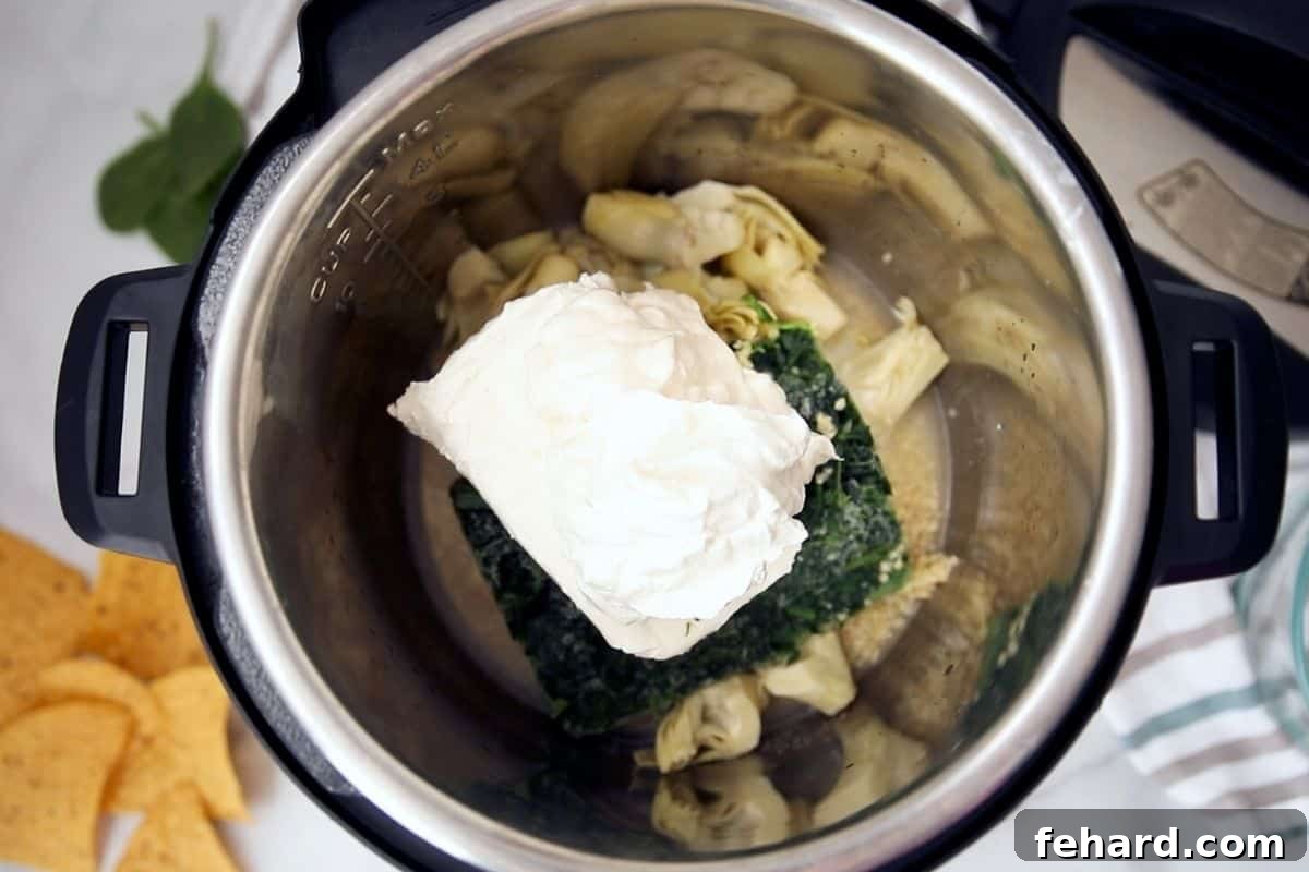 Spinach Dip Instant Pot Layered Ingredients for Spinach Artichoke Dip layered neatly inside an Instant Pot before cooking.