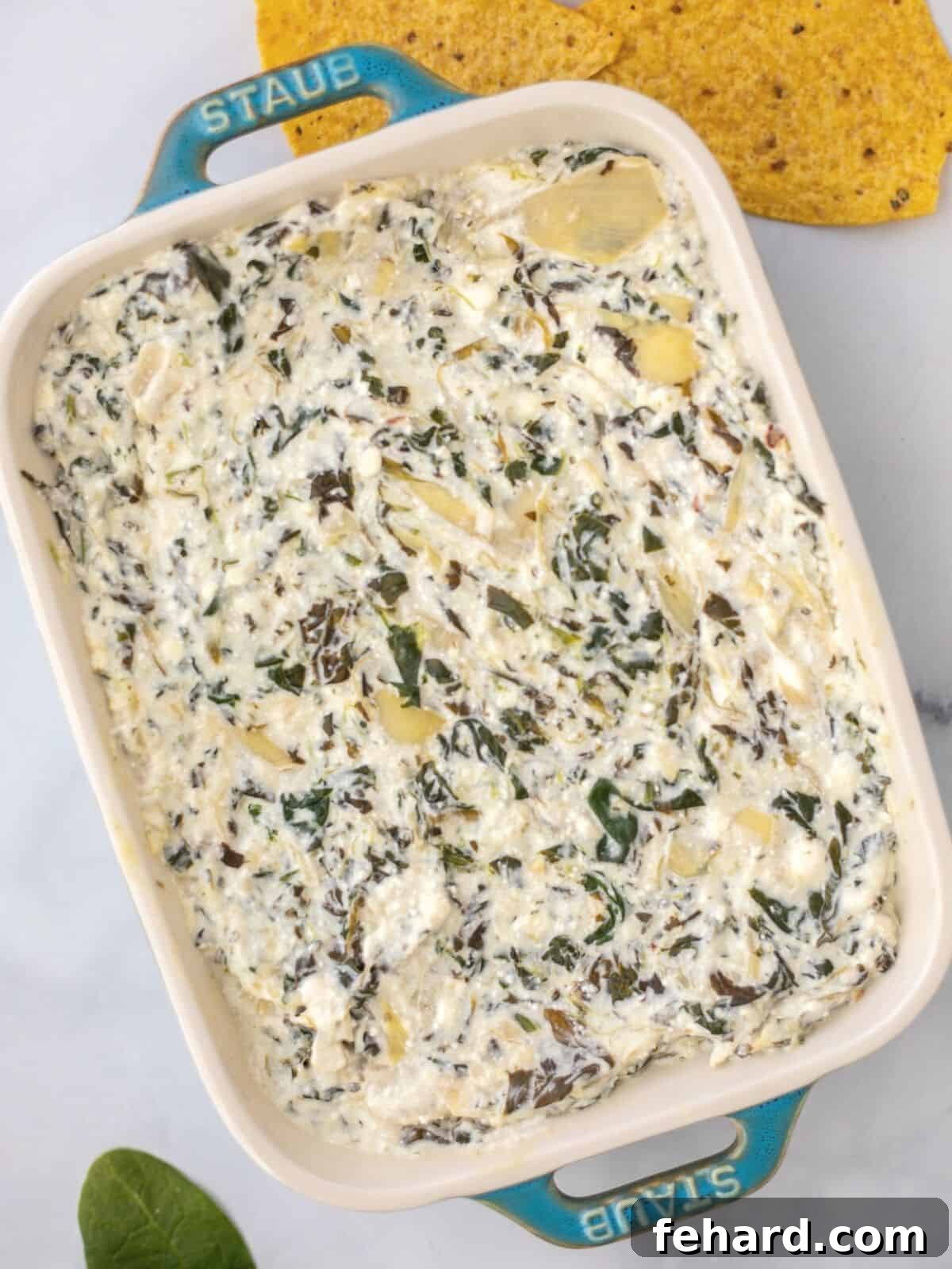 Instant Pot Spinach Artichoke Dip Serving Idea Delicious Instant Pot Spinach Artichoke Dip in a blue serving dish with tortilla chips and fresh spinach.
