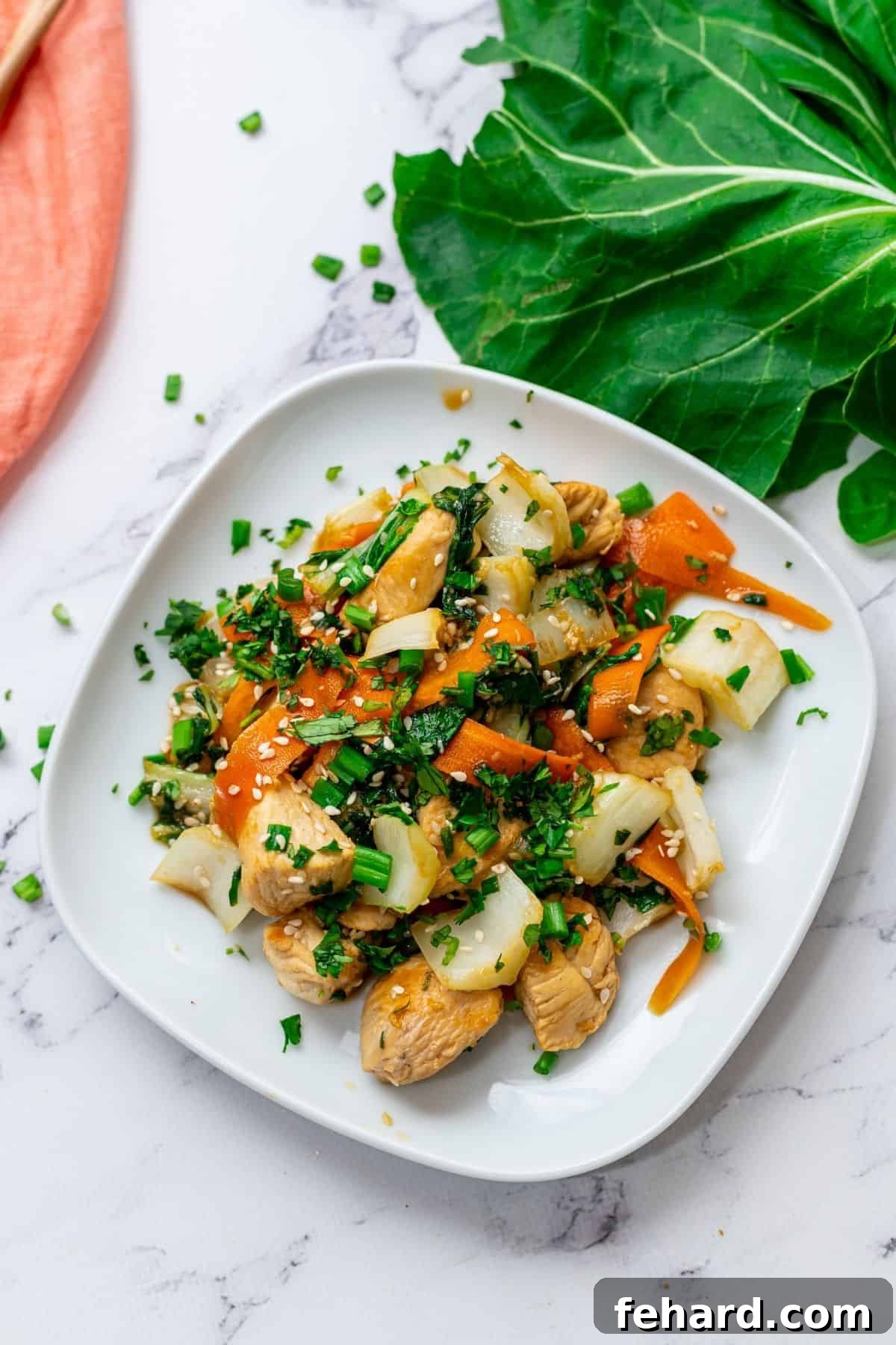 Delicious chicken and bok choy stir-fry with carrots and a soy honey sauce, garnished with sesame seeds and cilantro, served on a white plate.