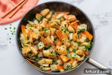 Chicken, bok choy, carrots, and a soy honey sauce tossed together in skillet.