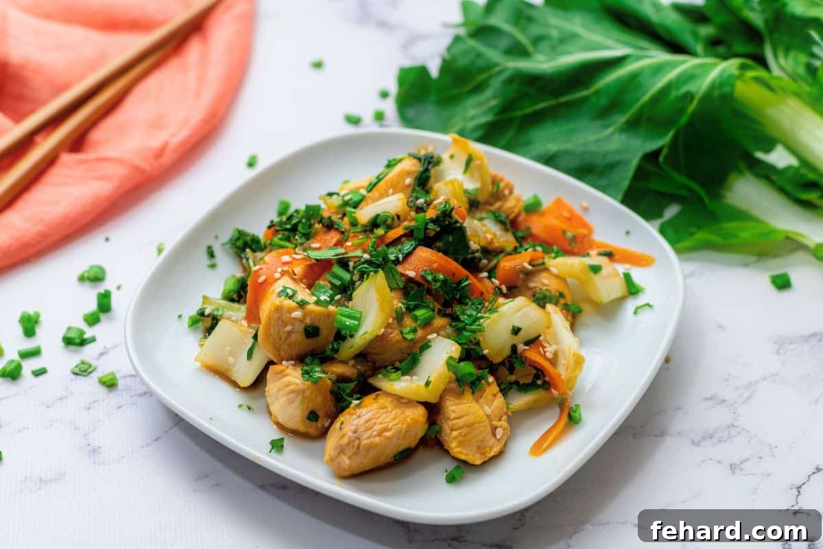 A beautifully plated chicken and bok choy stir-fry with carrots and a rich soy honey sauce, garnished with toasted sesame seeds and fresh green onions, ready to eat.
