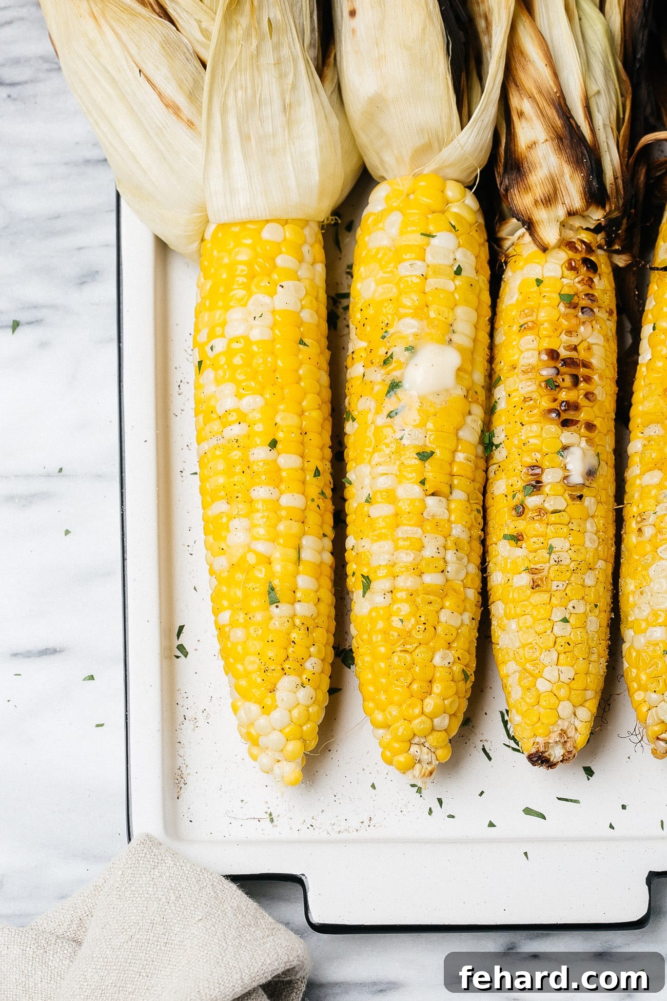 grilled corn on a cob on a white plate