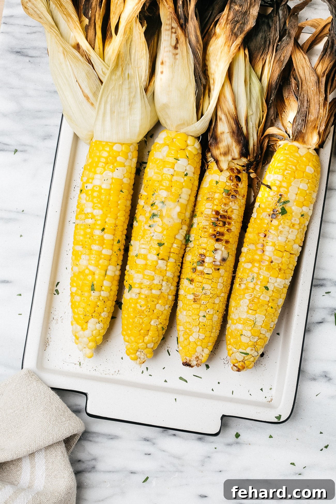 grilled corn on a cob on a white plate