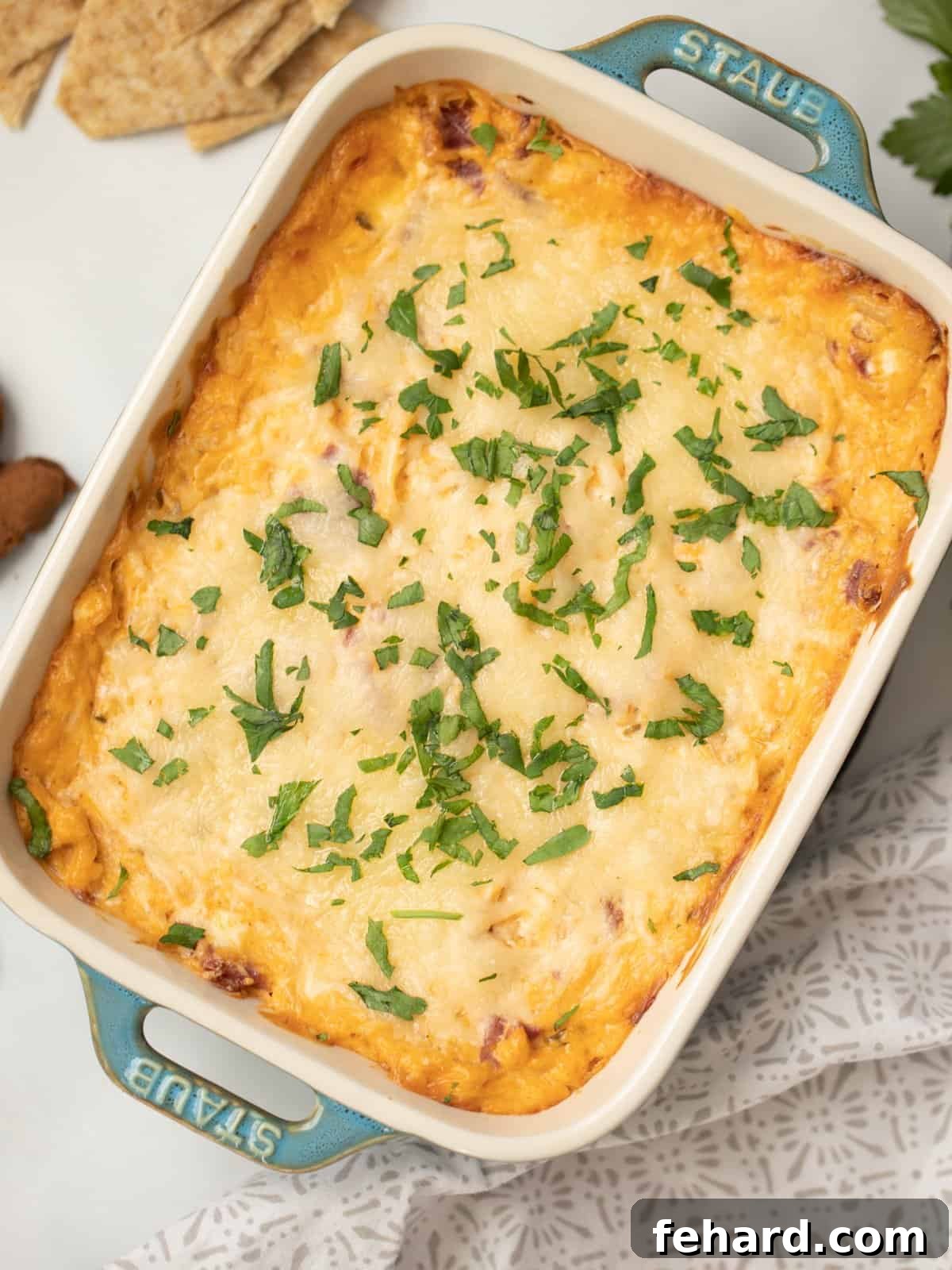 Hot Reuben dip in blue casserole dish topped with fresh parsley.