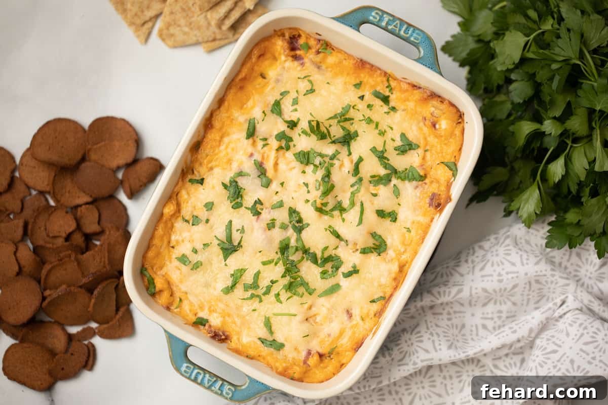 Baked Reuben Dip topped with fresh parsley next to triscuits and rye chips.
