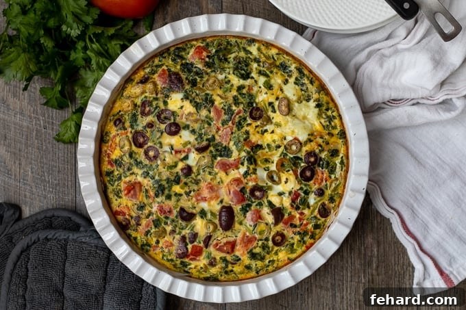 Golden-brown Baked Greek Frittata in a white baking dish, fresh from the oven, with a perfectly set texture.