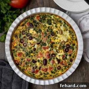 Baked Greek Frittata in a white pie dish, showcasing its golden-brown top and colorful Mediterranean ingredients.