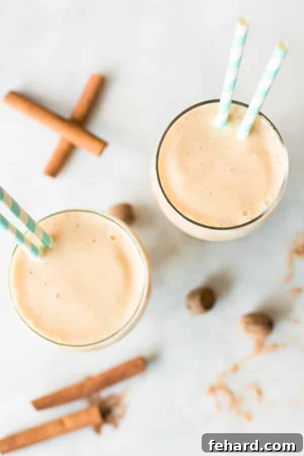 Overhead view of two clear cups filled with refreshing pineapple and peach smoothie, garnished with fresh fruit and ready to serve.