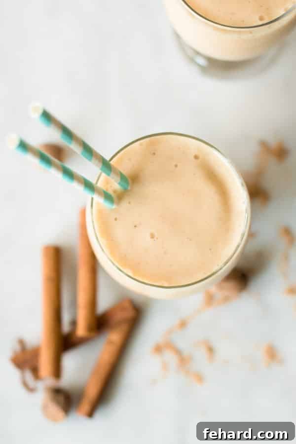 Close-up of a glass cup of Spicy Pineapple Peach Smoothie with two straws, beautifully showcasing its creamy, inviting texture.